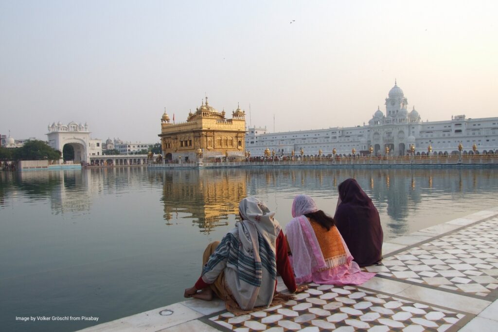 Zarándokok ülnek az amritsari Aranytemplom, a Harmandir Sahib szent tava mellett.