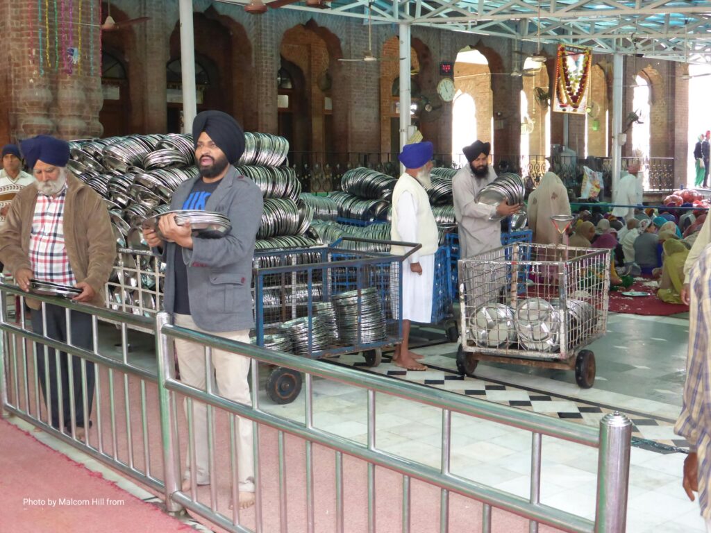 Seva a langarban: férfiak tányérokat készítenek elő a közös étkezéshez a gurdwarában.